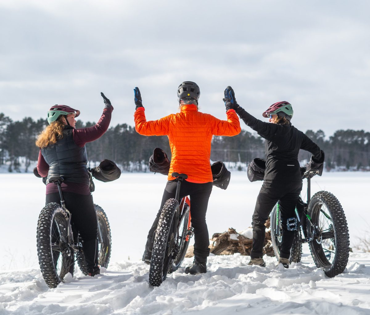 Women high-fiving on their electric bikes in the snow