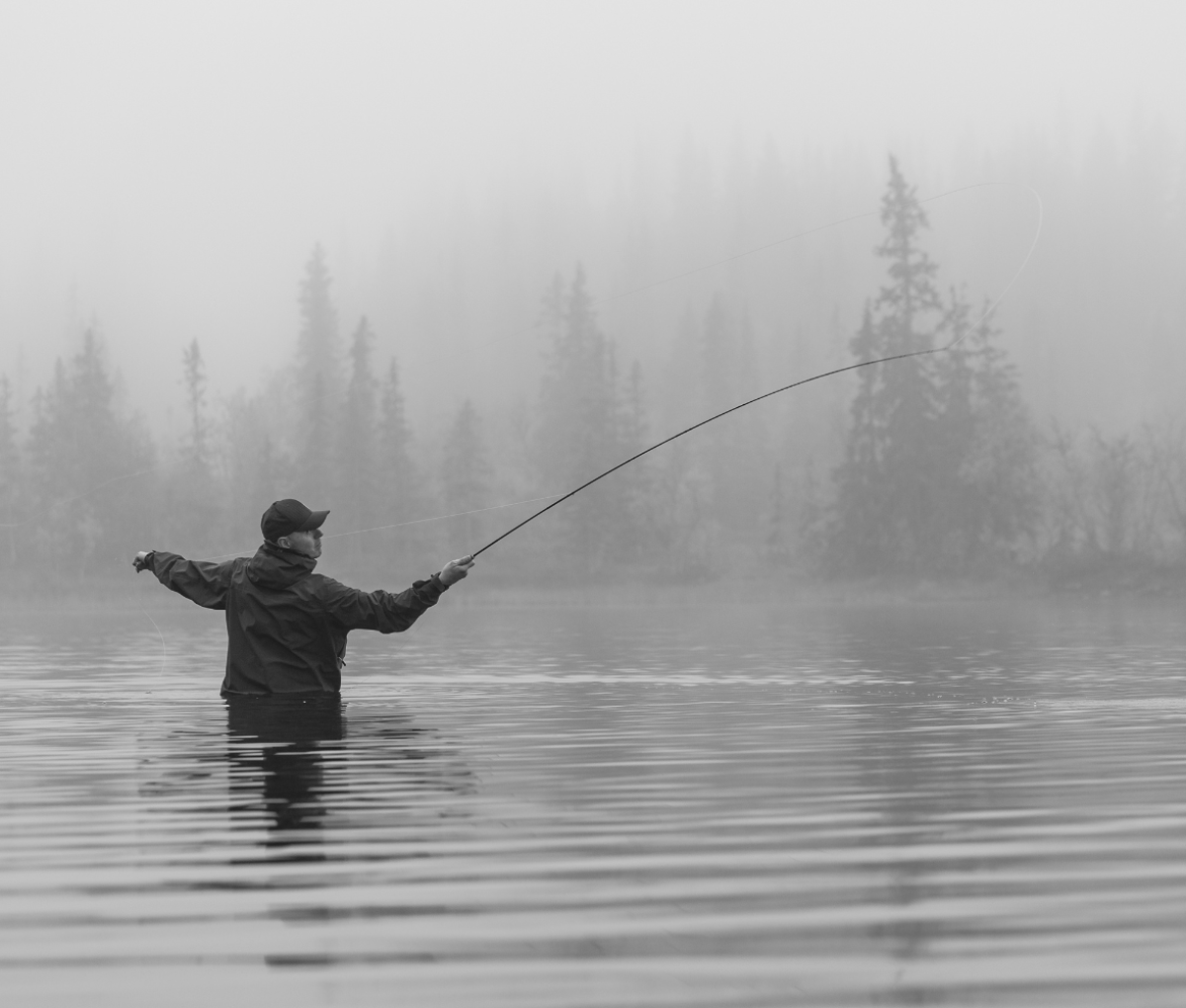 a person fly-fishing on a misty day in a lake in Jämtland Härjedalen,